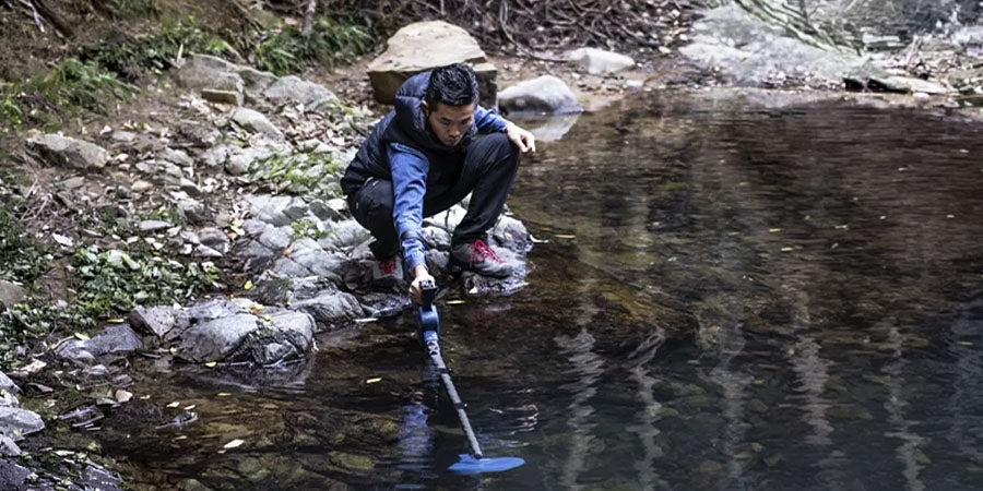 person metal detecting in a river with SDC 2300