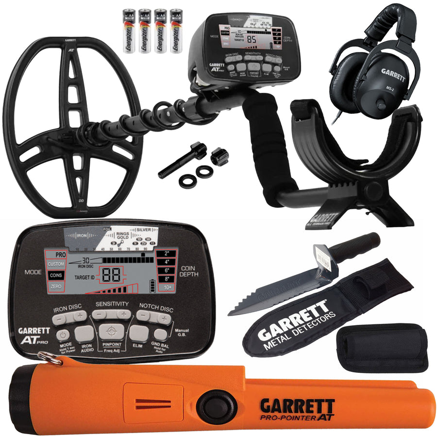 Garrett AT Pro metal detector kit with an orange and black handheld detector, a large black metal coil, a digital control unit, a pair of black over-ear headphones, a black stand, a black digger in a sheath, small hardware pieces, and four batteries on a white background.