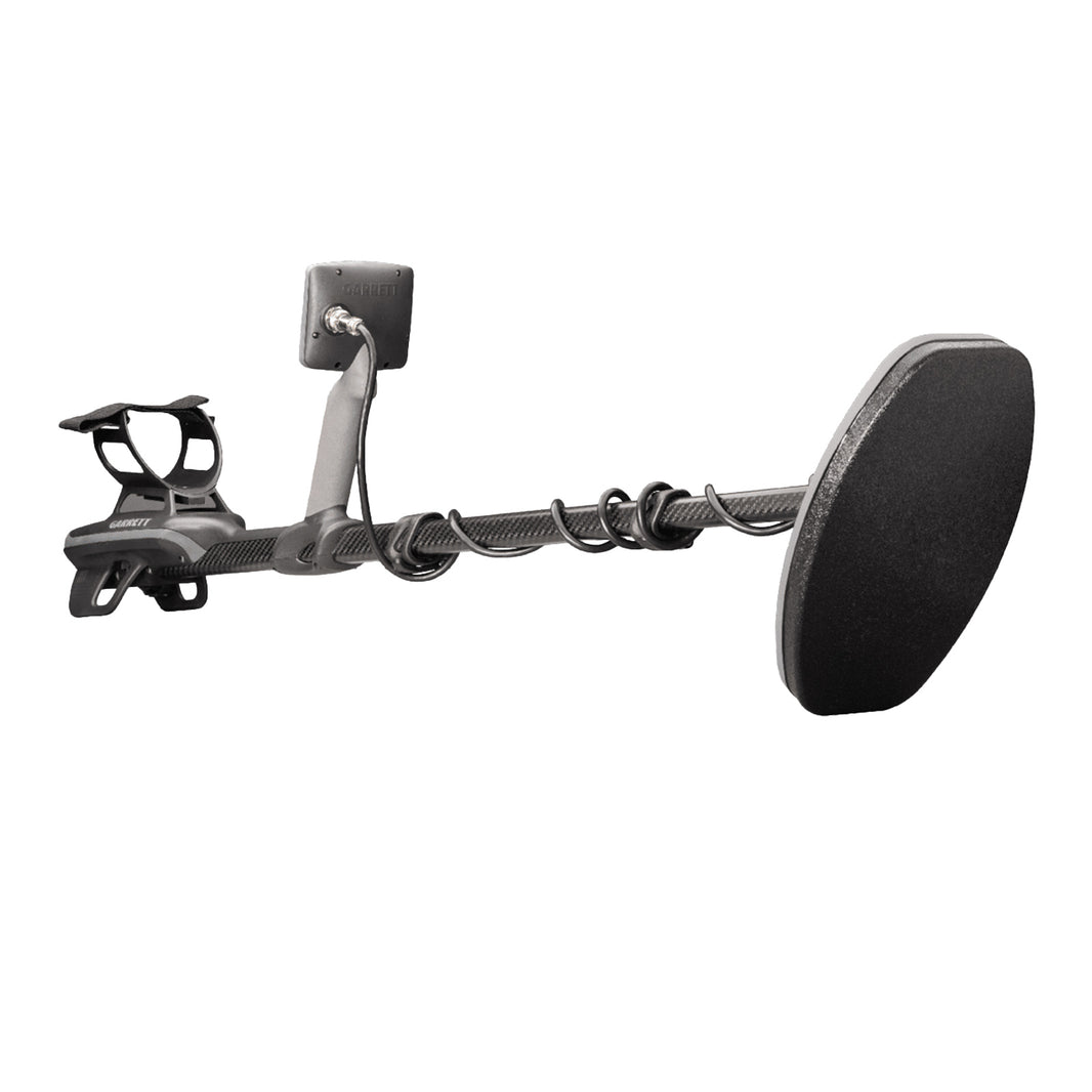 A black metal detector with a large coil, a textured handlebar grip, and a rectangular display screen, shown against a solid white background.