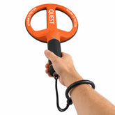 A hand holding a Quest Scuba Tector metal detector with an orange and black circular coil, wrist strap, and black handle grip against a solid white background.