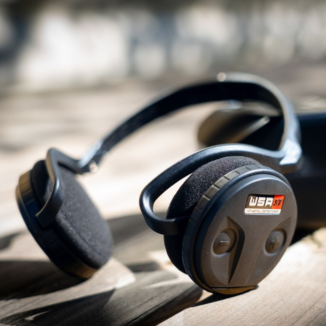 XP WSA ST wireless headphones with black ear cups and padded headband on sandy ground