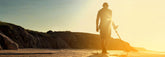 Detectorist hunting at sunset with a metal detector on a coastal hillside