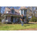 Detectorist swinging a Garrett ACE 400 on the lawn of an old two-story farmhouse