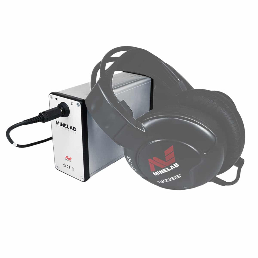 A Minelab lithium ion battery designed for powering metal detectors, with built-in amplifier. The battery is primarily silver with black and gray accents, featuring the Minelab brand logo and headphones plugged in