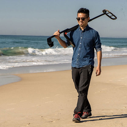 Man carrying the Minelab Go-Find 11 over his shoulder along the shoreline