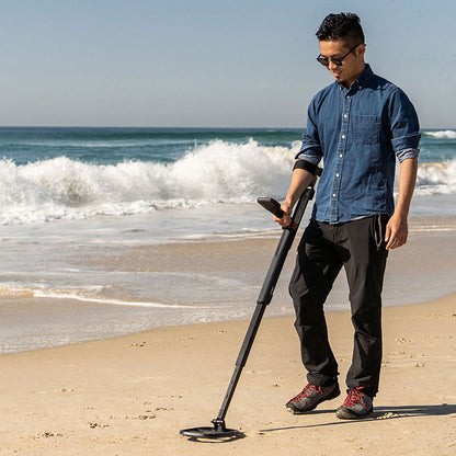 Man swinging the Minelab Go-Find 11 at the surf line on a sandy beach