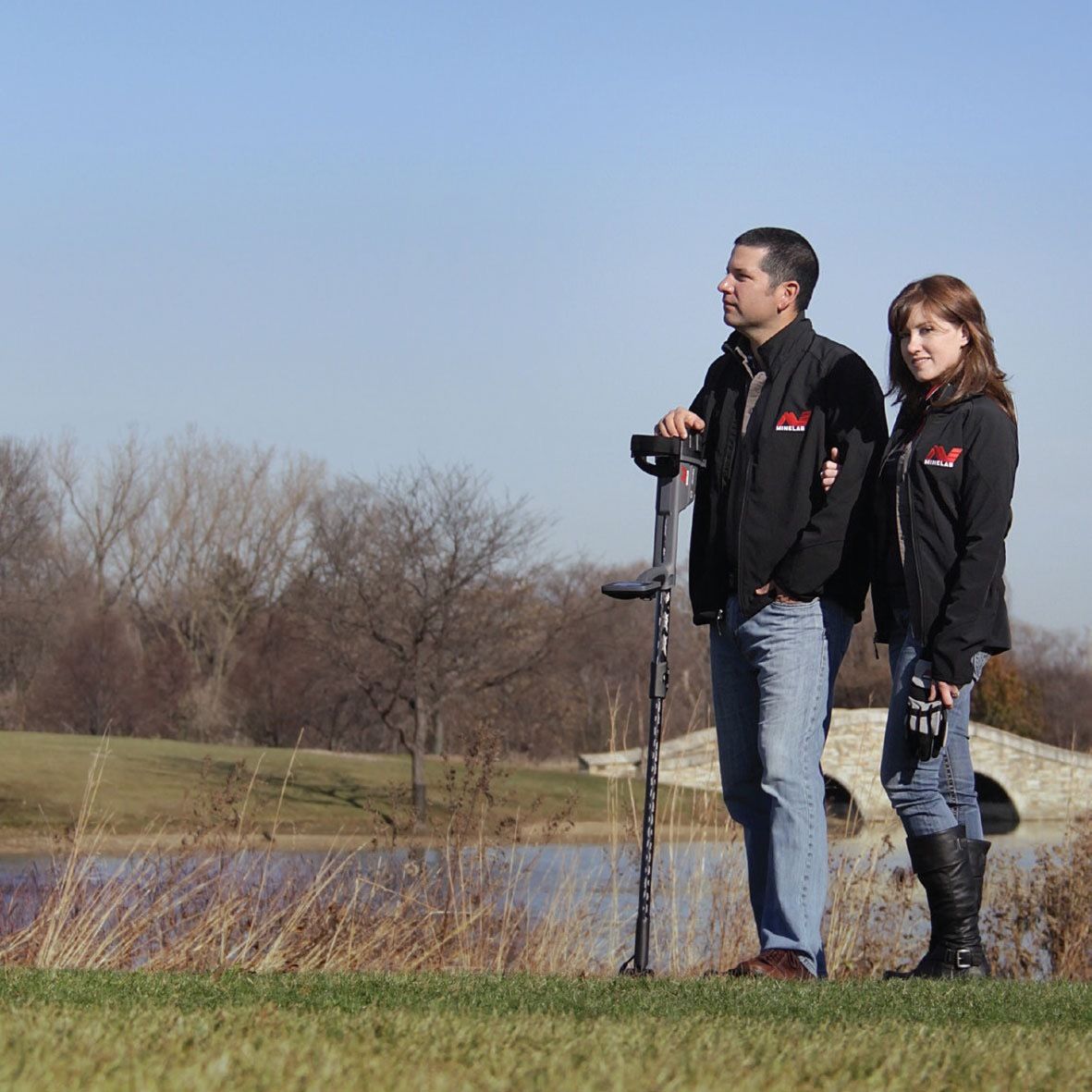 Detectorists in a park with a Minelab metal detector, one wearing Minelab digging gloves